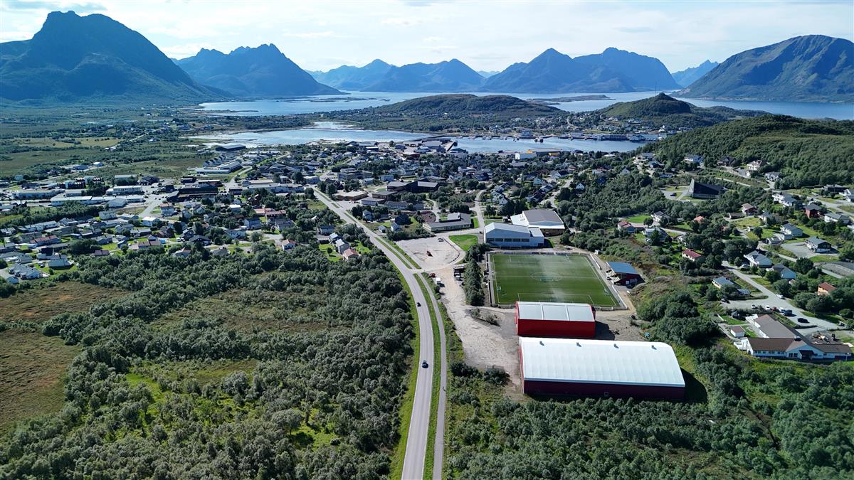 Dronebilde som viser Øksnes kommune, hallanlegg og fjellene i bakgrunnen
