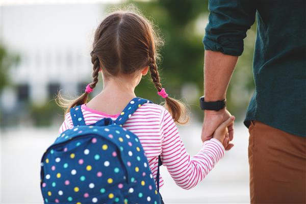 Jente på vei til skolen, holde forelder i hånden